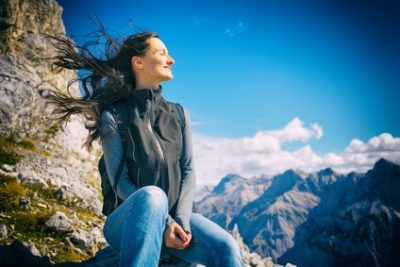 Das Foto zeigt eine Frau am Berg, sie wirkt glücklich und zufrieden mit sich und der Welt. Psychologische Beratung unterstützt einen besseren Umgang mit Stress.